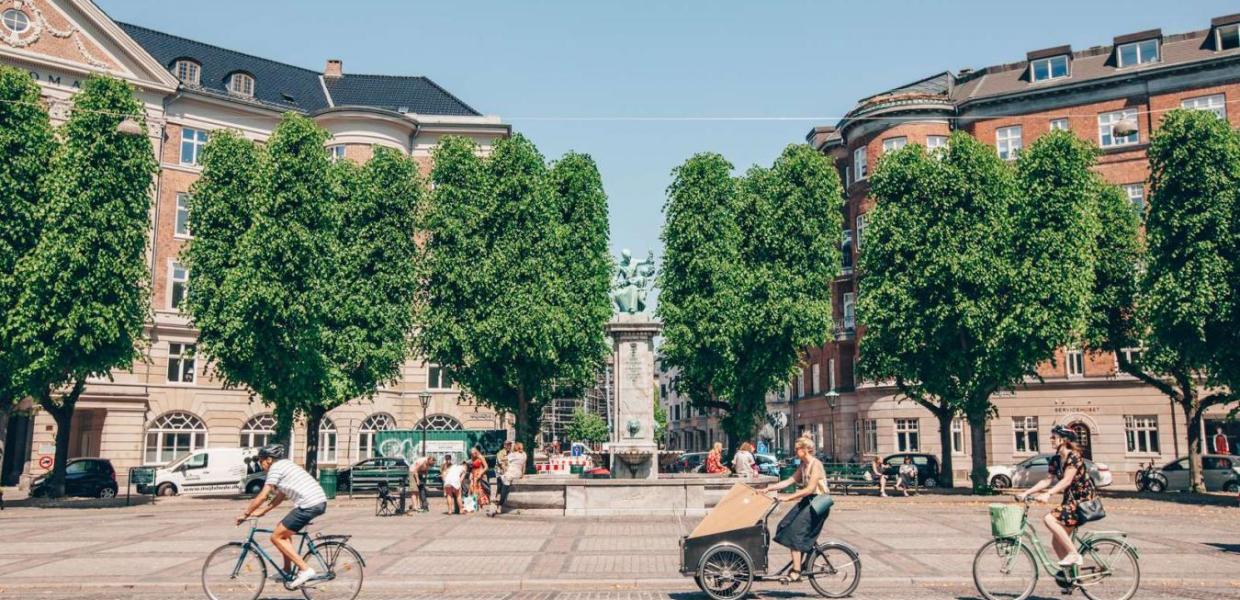 Cykler i solskin henover Sankt Thomas Plads på Frederiksberg.